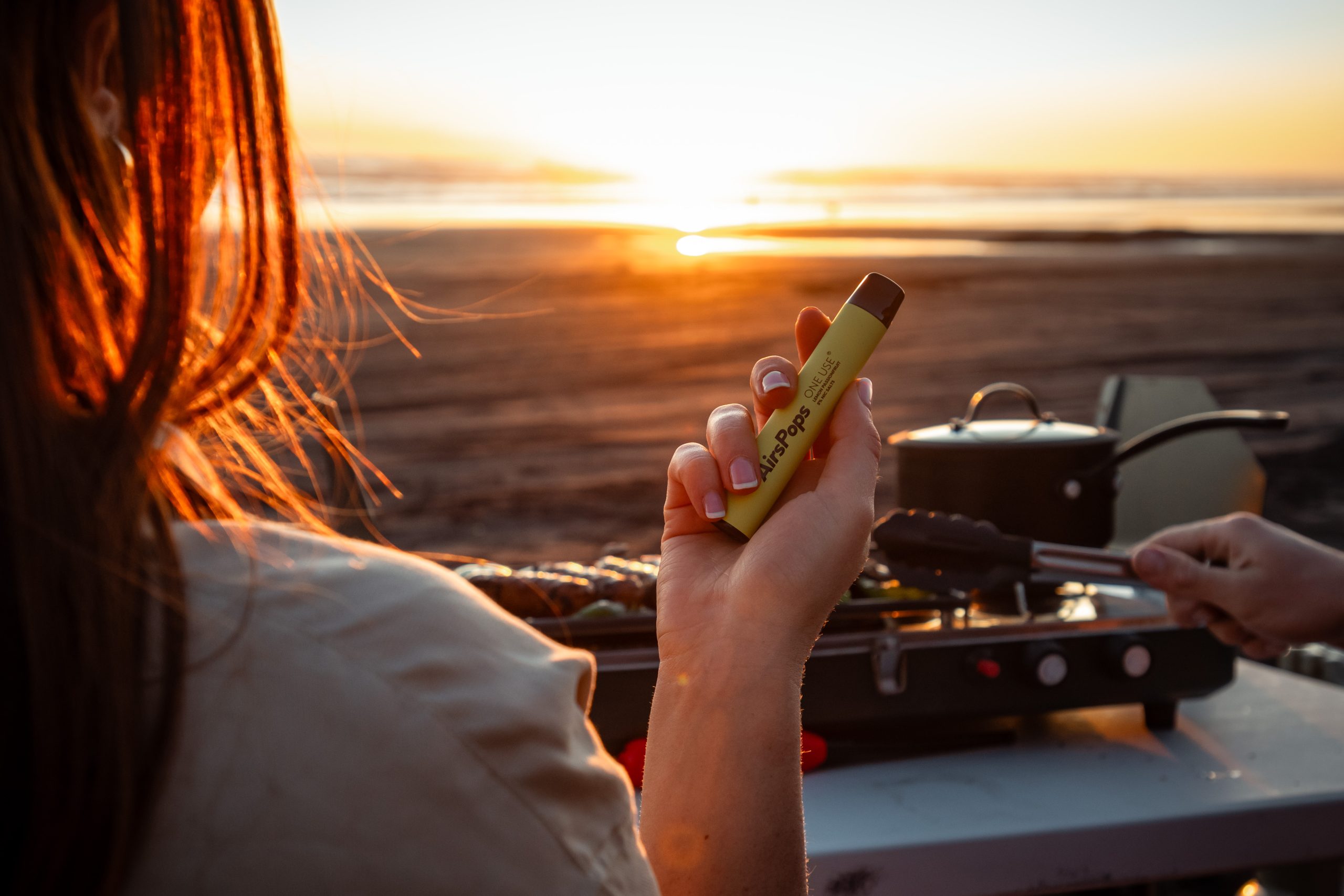 Bondi Beach sunset person relaxing with vape, golden hour beach vape - Vaping Redefined: Airscream UK
