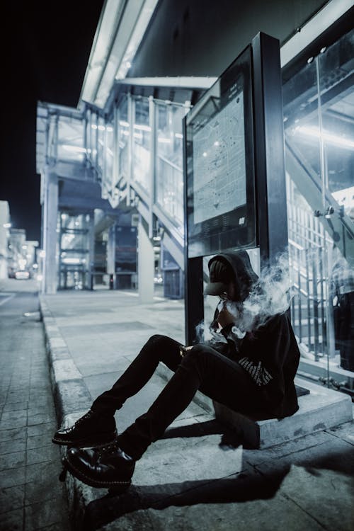 person vaping in Melbourne CBD, relaxing urban scene with vape, city skyscraper background vaping - Man sitting on a Side Street while smoking Vape · Free Stock Photo